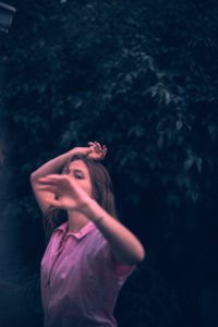 Vintage photo of a girl standing in front of a bush