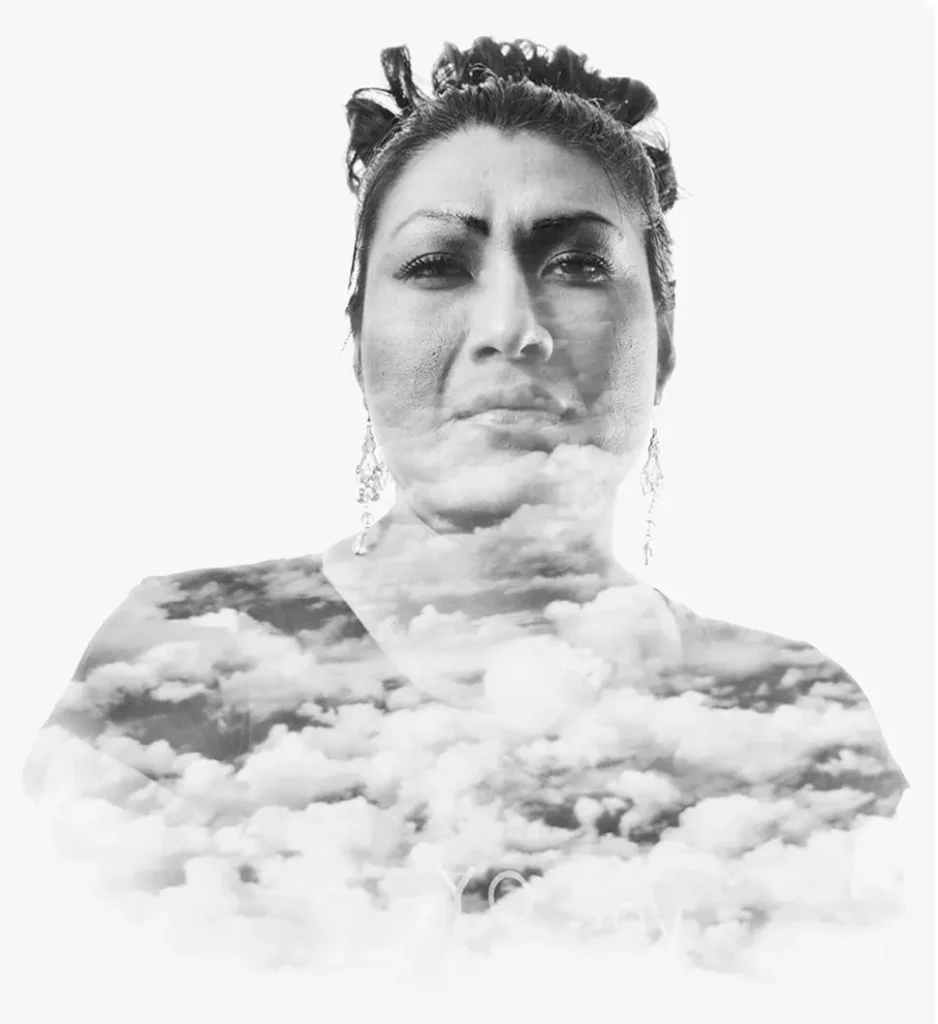 A black and white double exposure of a woman’s face blended with an image of clouds, creating a surreal, dreamy effect.