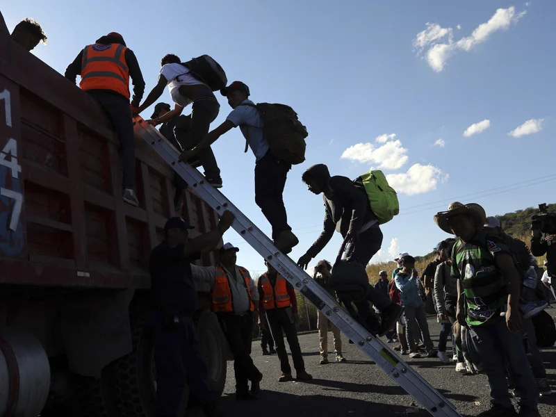 A group of people with backpacks climb a ladder into the back of a large red truck, while others stand nearby. The sky is clear with a few clouds.