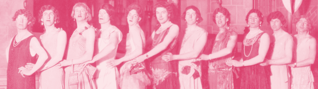 Ten people in dresses stand in a line, posing side by side with arms linked. The image has a pink tint and appears to be vintage.