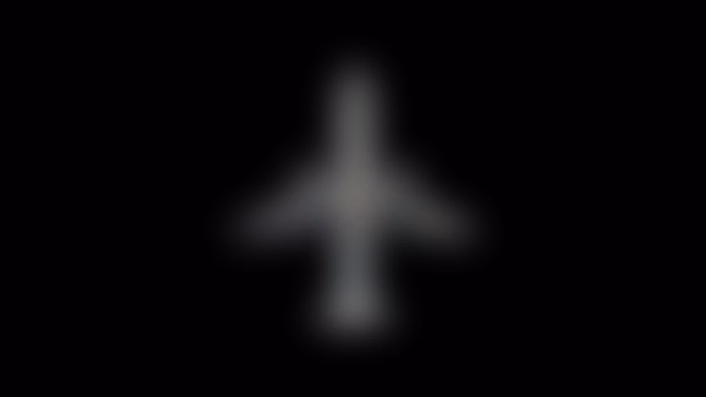 A blurry, gray silhouette of an airplane is centered on a black background.